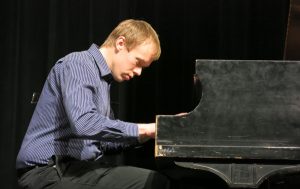 Music Clubhouse instructor Dan performs on piano on stage.