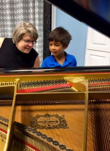 photo of Janet Hart Johnson at piano with a young boy during a piano lesson.