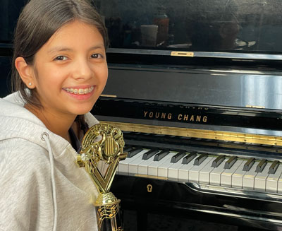 girl at piano with award